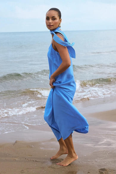 Blauwe MEXX jurk, losvallend en vloeiend, met een bijpassende sjaal over de schouder, gedragen op een strand.