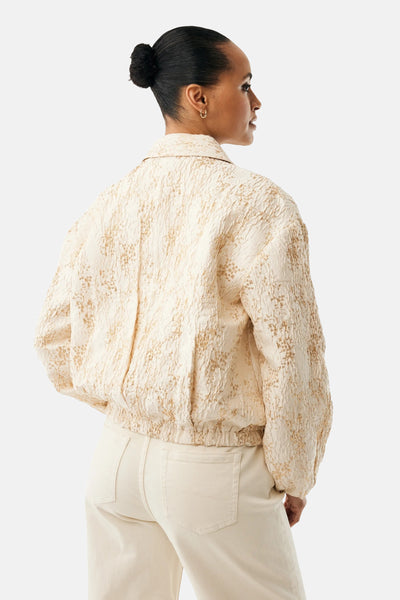 Veste courte beige de MEXX avec un motif texturé, portée avec un pantalon assorti, vue de dos.