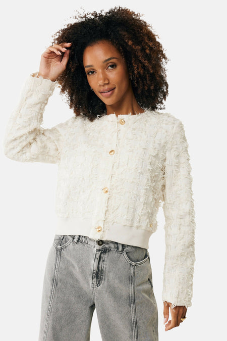 Veste courte écru de MEXX, avec des boutons dorés et une texture bouclée, portée avec un jean gris.