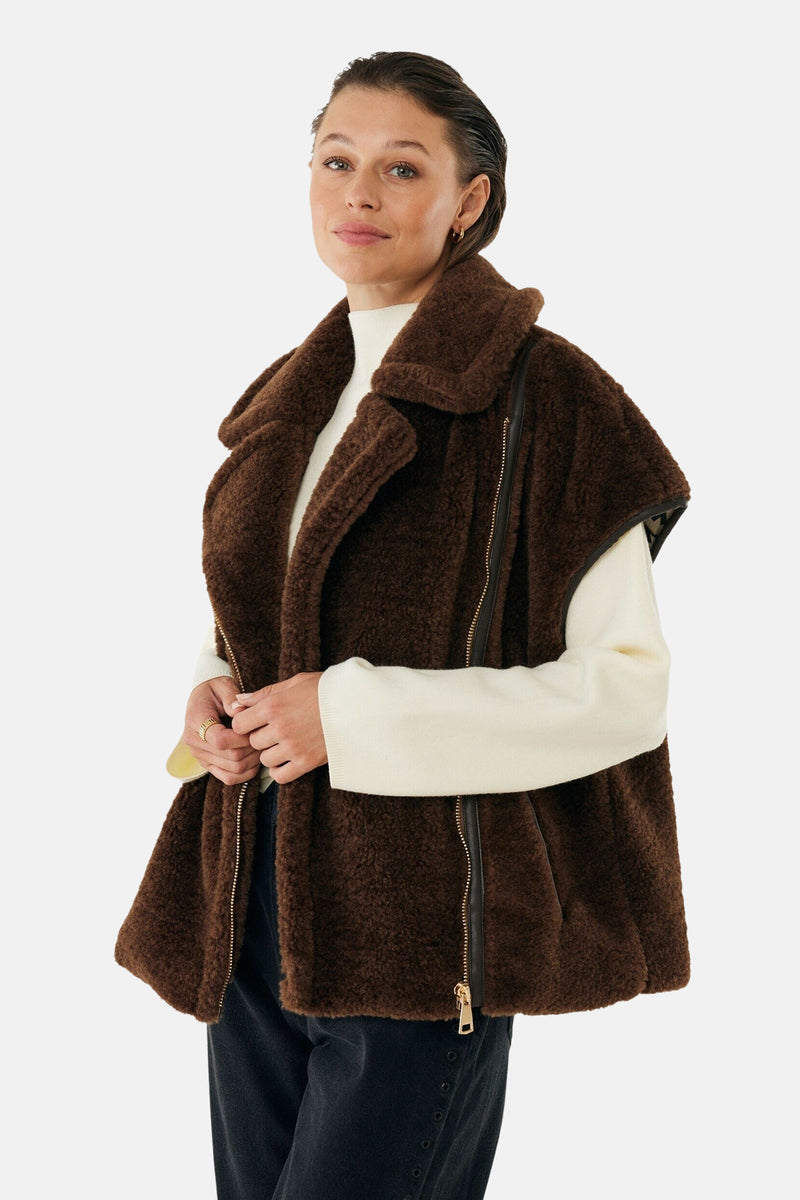 Bruin pluche mouwloos vest van MEXX met gouden ritssluiting, gedragen over een witte trui.