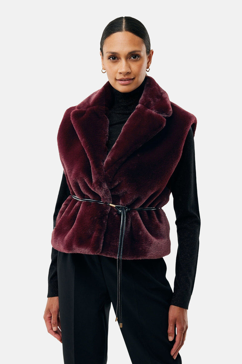 Bordeaux mouwloos vest van MEXX, brede imitatiebontkraag, gedragen over een glanzende zwarte coltrui.