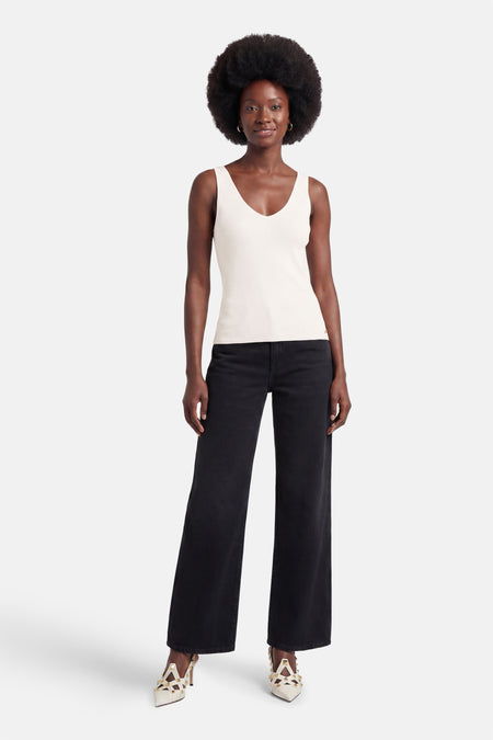 Débardeur blanc de MEXX côtelé à col en V, porté avec un jean noir et des escarpins cloutés.