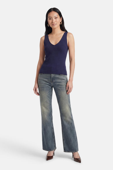Top côtelé bleu marine de MEXX à col en V, porté par une femme avec un jean délavé et des escarpins bruns.