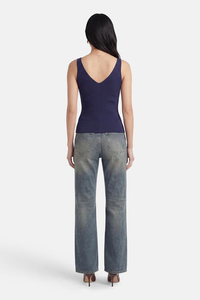 Débardeur bleu marine côtelé de MEXX avec col en V profond au dos, porté avec un jean.