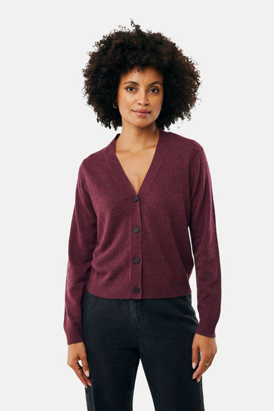 Bordeaux fijngebreid vest van MEXX, gedragen met een zwarte broek met knopen aan de zijkant.
