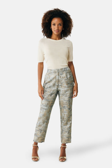 Top écru de MEXX, manches courtes, porté avec un pantalon à motif texturé et des sandales dorées.
