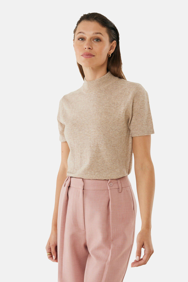 Beige ronde hals trui van MEXX, gedragen met een roze broek met hoge taille, gouden oorbellen.