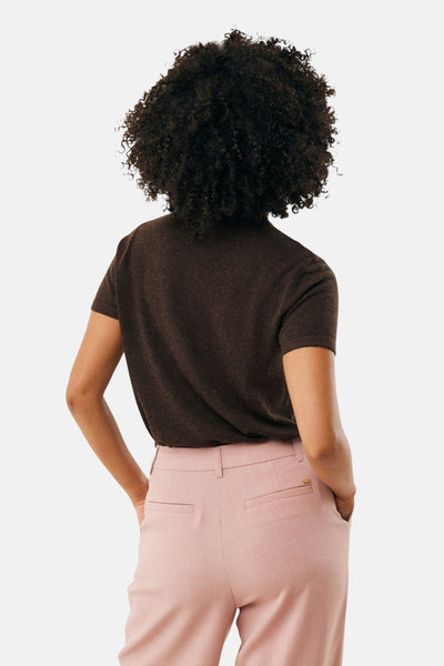 Bruine ronde kraag pull van MEXX, gedragen met een roze broek en de handen in de zakken.