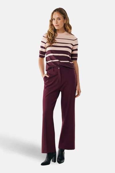 Multikleuren rondehals trui van MEXX, gedragen met een bordeauxrode wijde broek en zwarte enkellaarsjes met hak.
