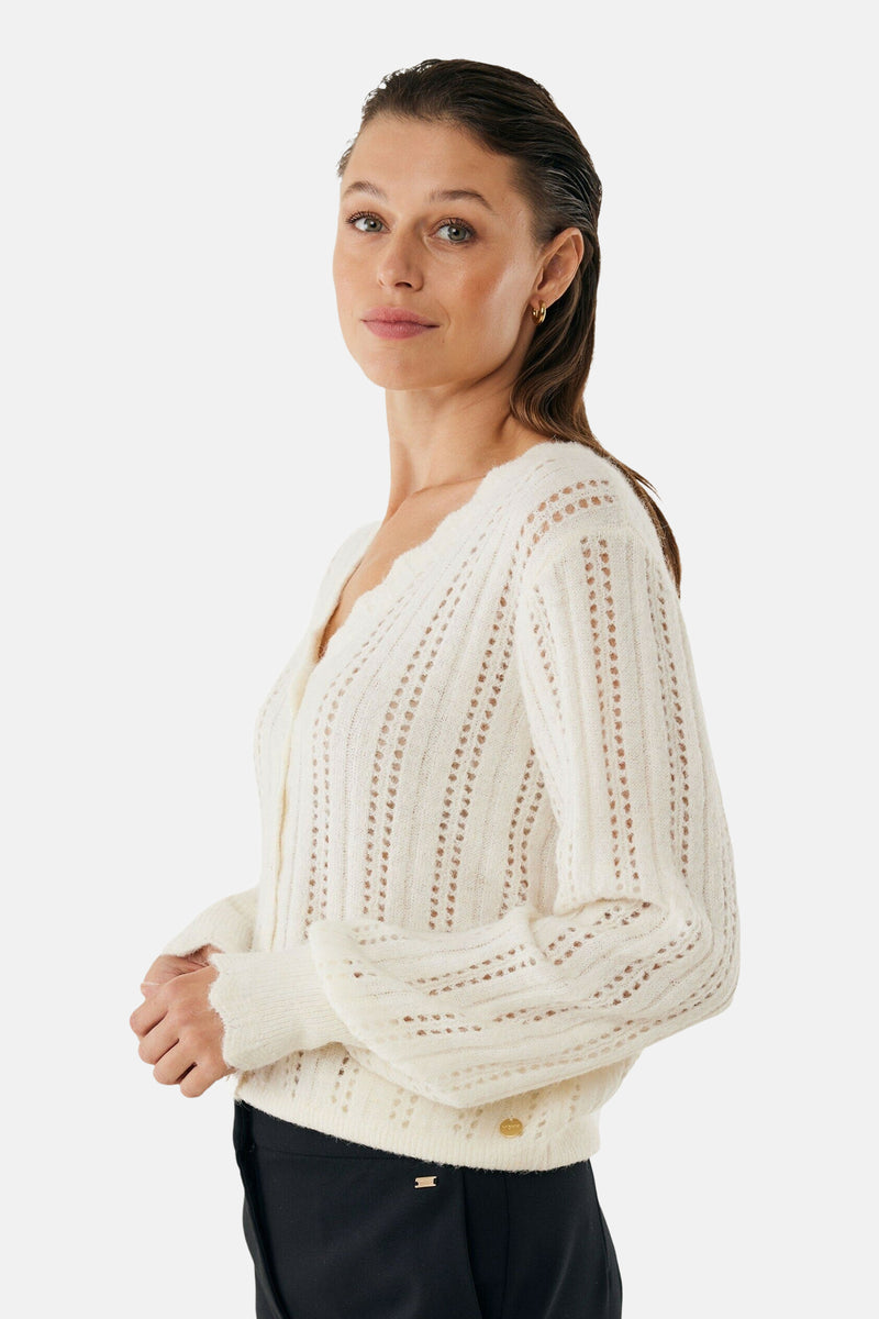 Ecru gebreid vest met open structuur van Mexx, gedragen met een zwarte broek.