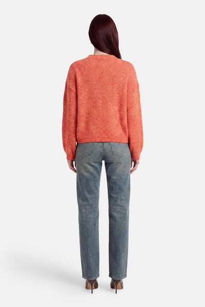 Pull orange de MEXX en maille texturée, ample à col rond, porté de dos avec un jean délavé.