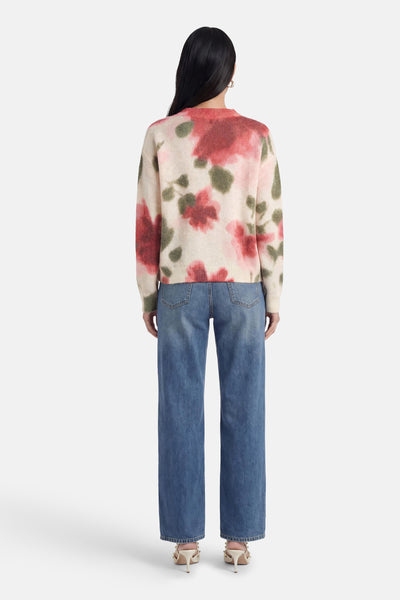 Pull multicolore de MEXX en maille duveteuse à motif floral rouge et vert, col ras-du-cou, vue de dos, porté avec un jean bleu et des talons beiges.