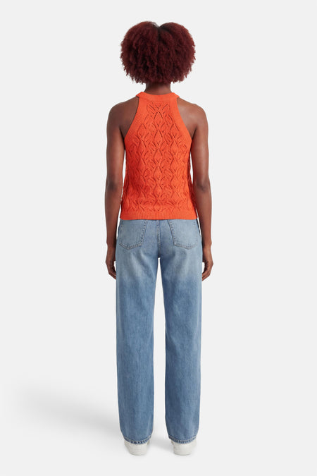 Top sans manches orange par MEXX, avec un motif en maille ajourée, porté avec un jean bleu ample.
