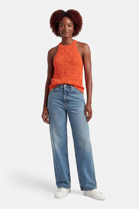 Top sans manches orange de MEXX à motif ajouré porté avec un jean ample et des baskets blanches.
