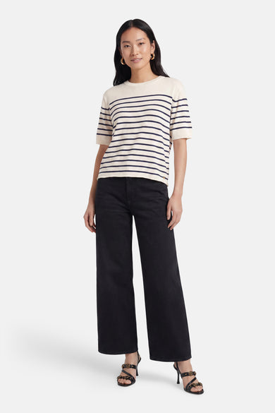 Pull multicolore de MEXX, crème à rayures bleu marine, col rond et manches courtes, porté avec un jean noir et des sandales.