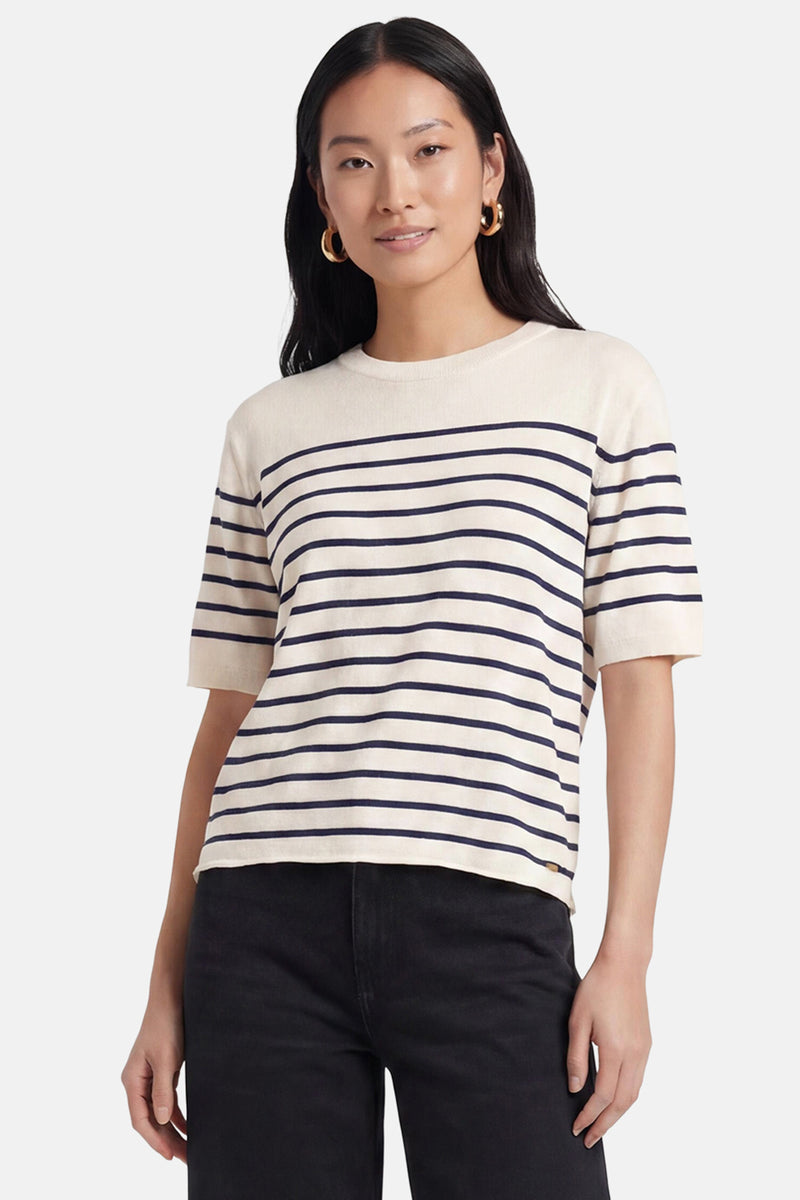 Pull rayé crème et bleu marine de MEXX, à col rond et manches courtes, porté par une femme en pantalon noir et boucles d'oreilles dorées.