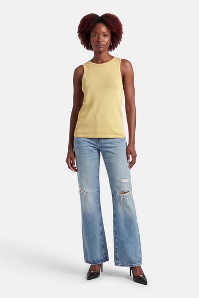 Débardeur jaune, de MEXX, avec texture côtelée, porté avec un jean bleu délavé déchiré et des escarpins noirs.
