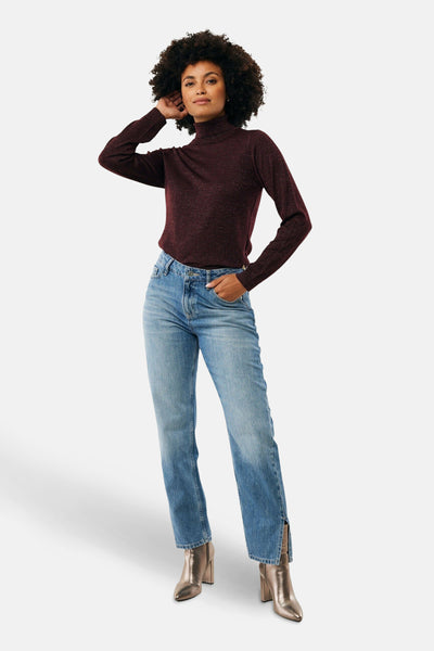 MEXX glanzend rode coltrui, gedragen met een blauwe jeans en metallic enkellaarsjes met hak.