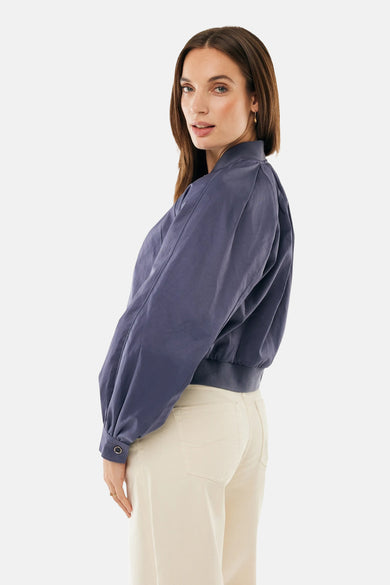 Veste courte bleue de MEXX, avec manches bouffantes et finitions bord-côtes, portée avec un pantalon beige.