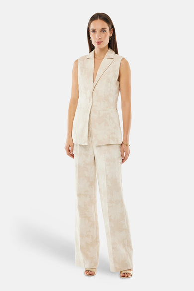 Pantalon beige par MEXX, coupe droite avec un motif floral délicat, porté avec un gilet assorti.
