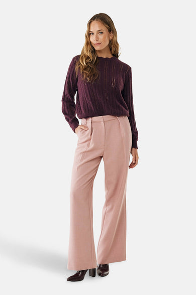 Roze broek van MEXX, uitlopend model, gedragen met een bordeauxrode kanten trui en bruine hakken.