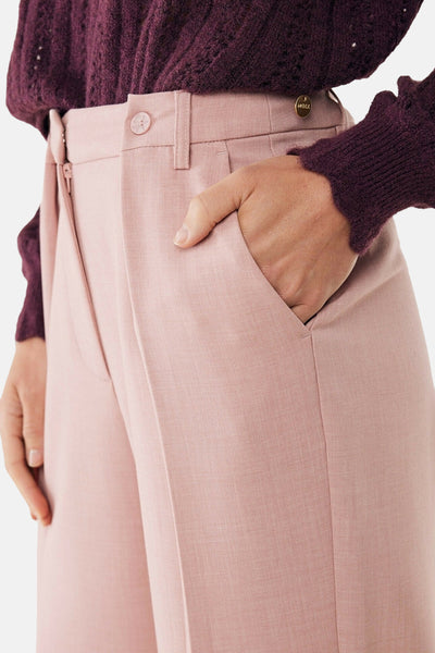Roze broek van MEXX met een hand in de zak, gedragen met een bordeauxrode trui.