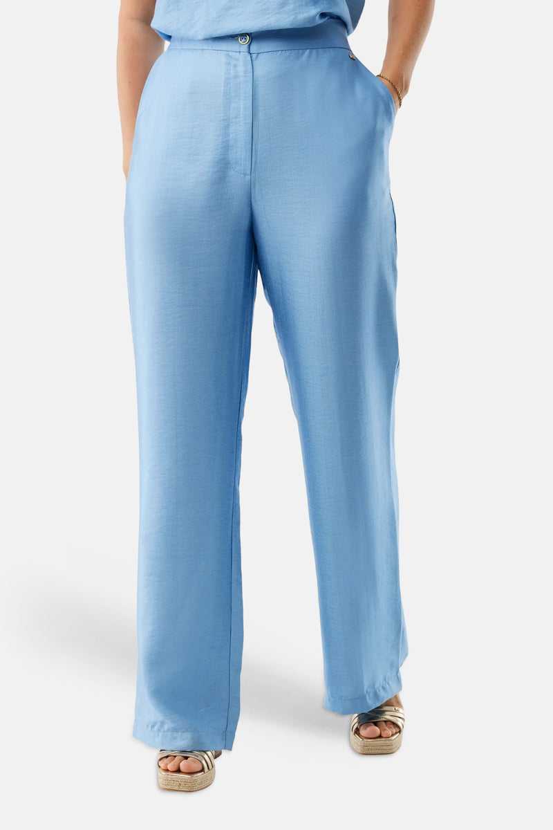 Pantalon bleu de MEXX avec une texture subtile, porté avec des sandales à plateforme dorées.