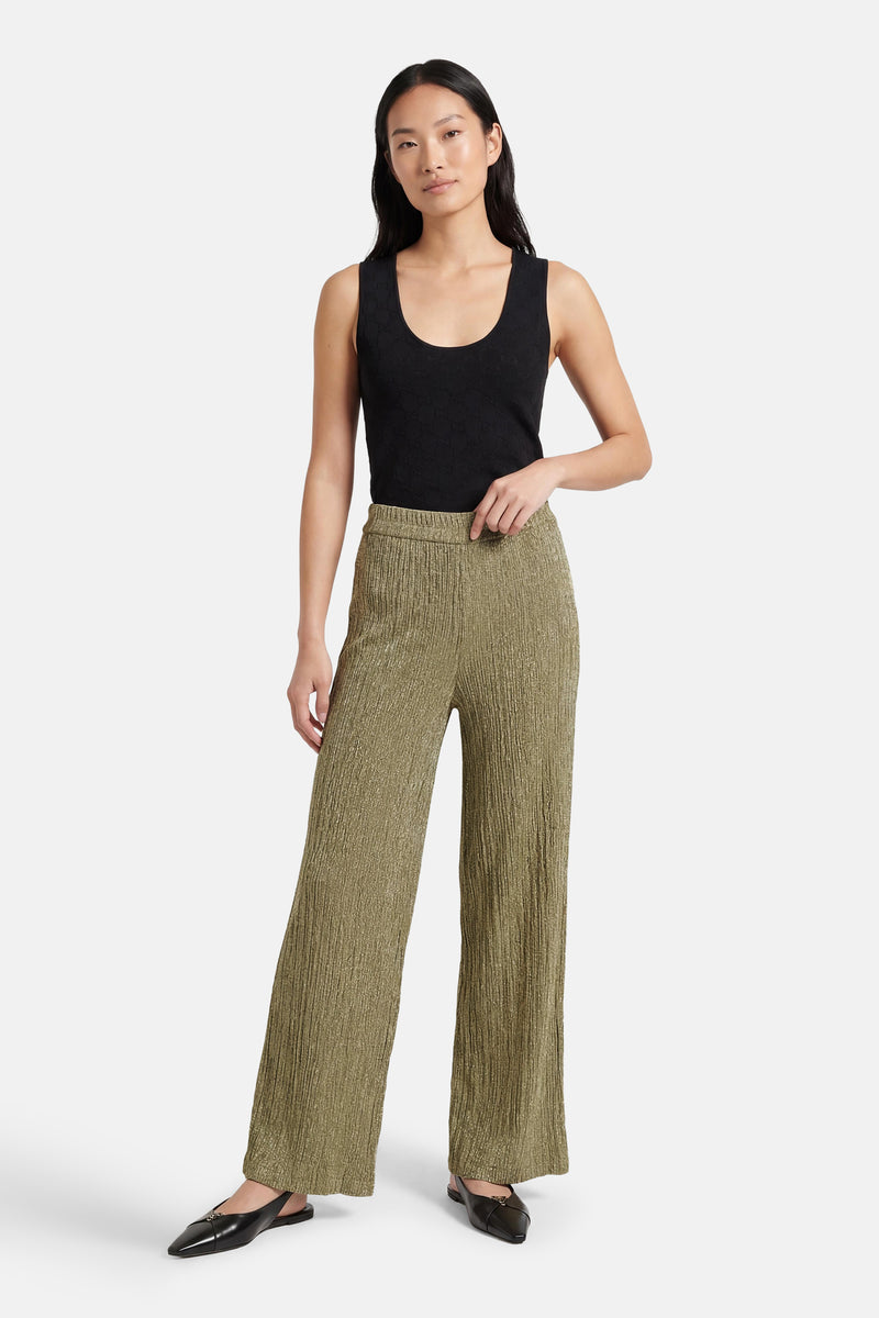 Gouden broek van MEXX, getextureerd, met een losse pasvorm en zichtbare zwarte schoenen.
