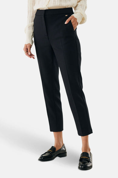 Pantalon chino 7/8 noir de MEXX, porté avec des mocassins noirs vernis et un pull en maille ajourée.
