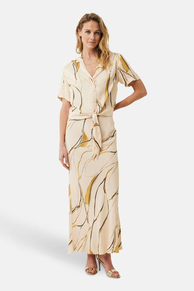 Lange veelkleurige rok van MEXX met abstract patroon, strik in de taille en gouden schoenen.