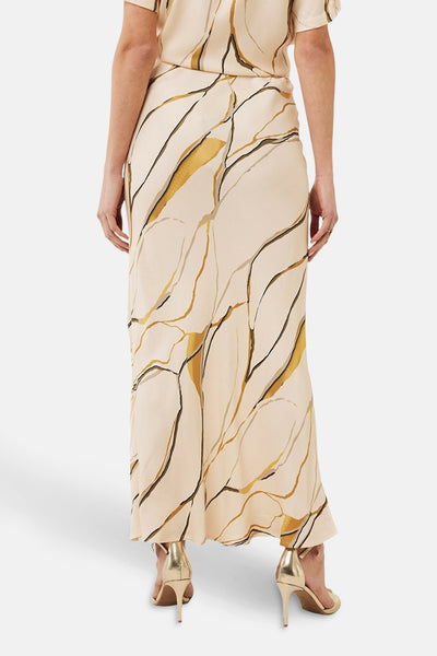 Jupe longue multicolore de MEXX, avec motif abstrait, portée avec des talons aiguilles dorés.
