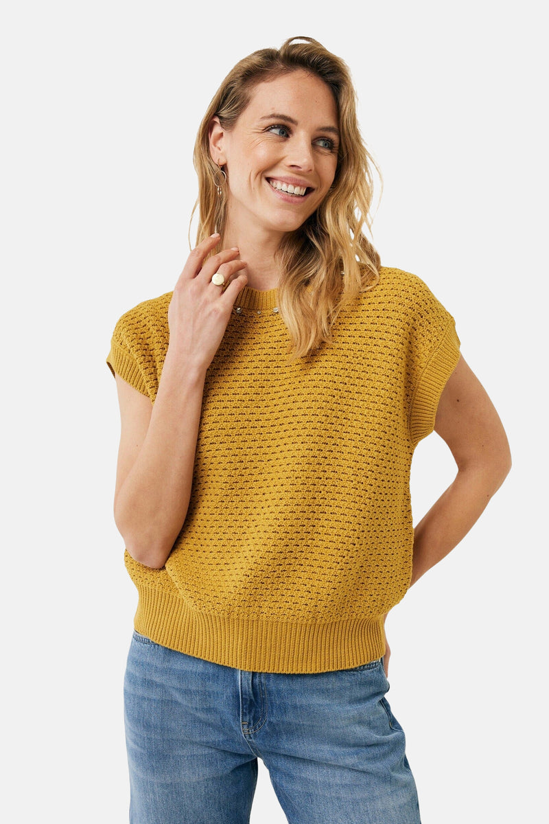 Pull à col rond jaune de MEXX avec texture tricotée porté avec un jean bleu.