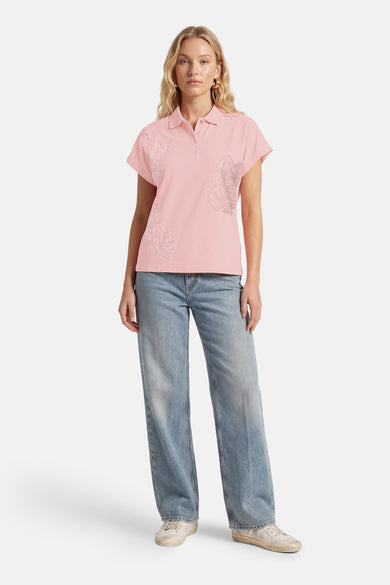 T-shirt rose de MEXX, orné de motifs floraux scintillants, porté avec un jean et des baskets.