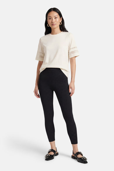 T-shirt blanc à manches courtes de Mexx, orné de dentelle aux manches, porté avec un pantalon noir à motif floral.