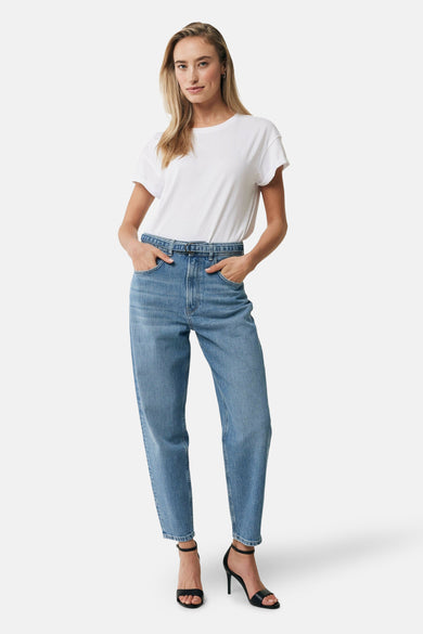 T-shirt blanc à manches courtes de MEXX, porté avec un jean bleu et des talons aiguilles noirs.
