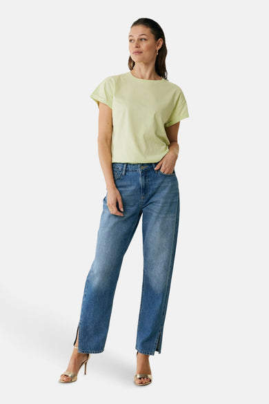T-shirt vert à manches courtes de Mexx, porté avec un jean et des talons hauts dorés.