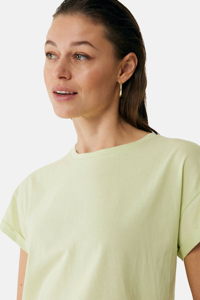 Lichtgroen T-shirt met korte mouwen van MEXX, gedragen met gouden oorbellen.