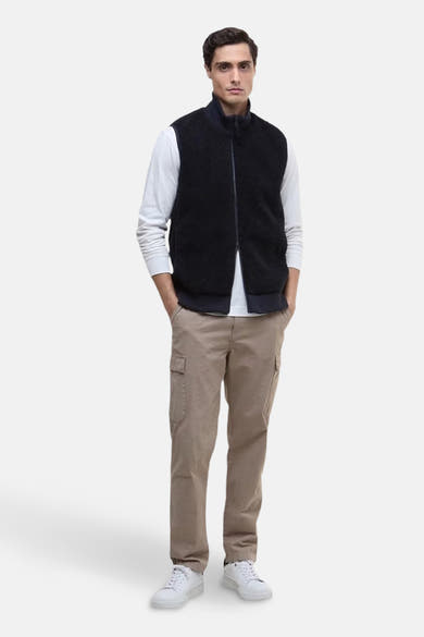 Blauwe fleece bodywarmer van BARBOUR, gedragen over een T-shirt met lange mouwen en een beige cargobroek.