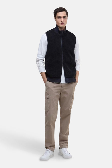 Blauwe fleece bodywarmer van BARBOUR, gedragen over een T-shirt met lange mouwen en een beige cargobroek.