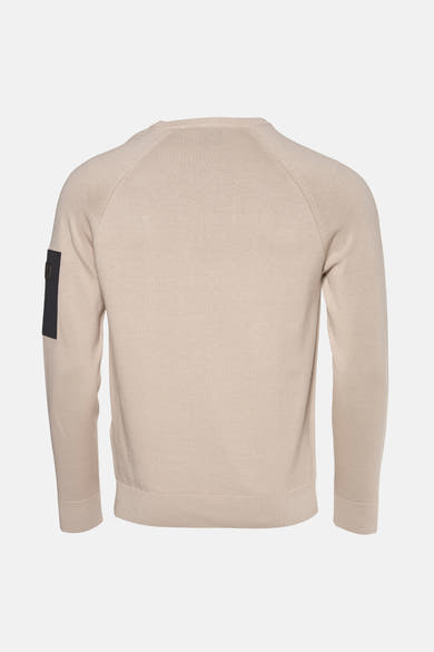 Beige ronde hals trui van Barbour, met een zwart label op de linkermouw, van achteren gezien.
