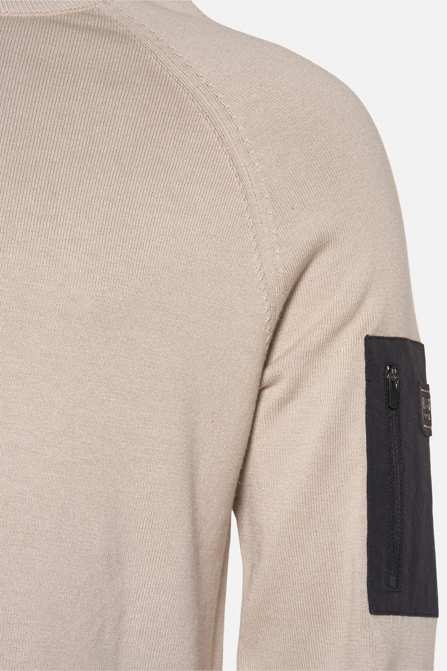 Beige ronde hals trui van Barbour, met een zwarte zak met rits op de linkermouw.