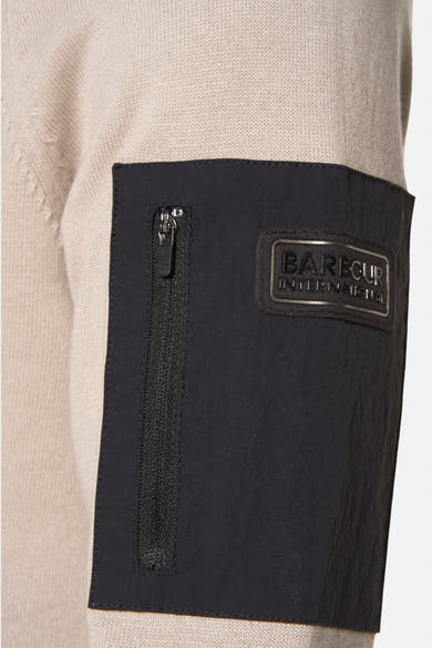 Beige ronde hals trui van BARBOUR, met zwarte opgestikte zak met rits en logo op de mouw.