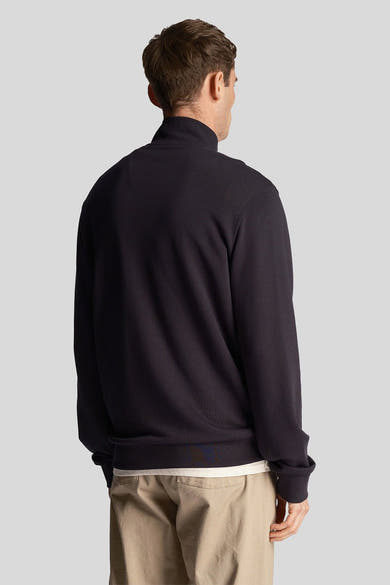 Blauwe sweater met opstaande kraag van LYLE & SCOTT, gedragen met een beige broek, achtergezicht.