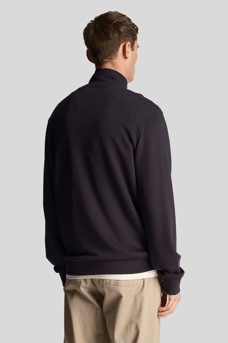 Blauwe sweater met opstaande kraag van LYLE & SCOTT, gedragen met een beige broek, achtergezicht.
