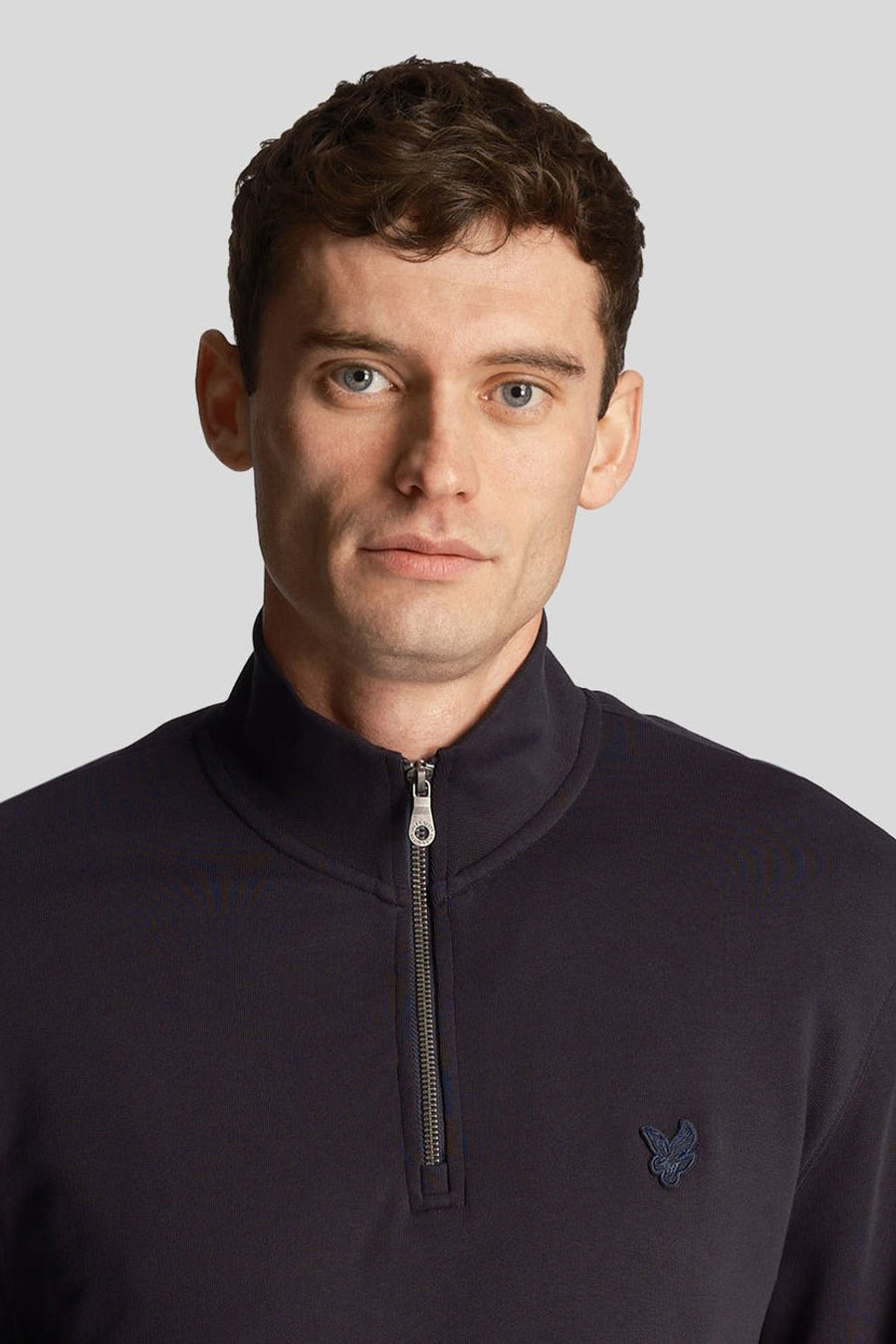 Blauwe sweater met opstaande kraag van LYLE & SCOTT met ritssluiting en geborduurd logo op de borst.