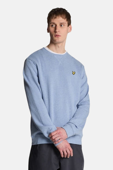 Sweat-shirt bleu de LYLE & SCOTT, avec un col rond blanc, porté avec un pantalon gris.