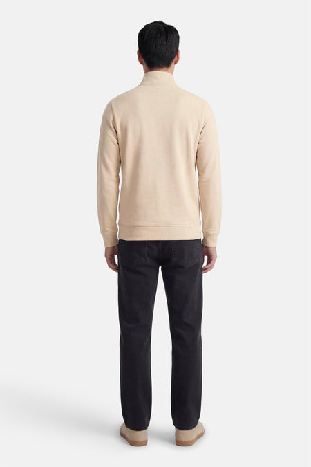 Beige sweater met opstaande kraag van LYLE & SCOTT, gedragen met een zwarte jeans en crèmekleurige schoenen, achterzicht.