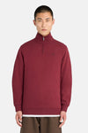 Burgundy half-zip sweatshirt with ribbed cuffs and hem, featuring small embroidered logo on chest, front view on model wearing white tee and brown pants