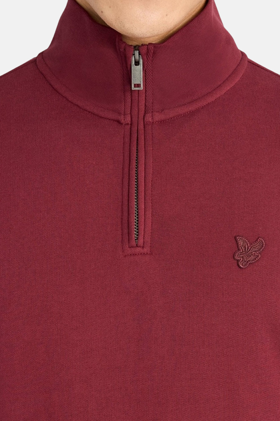 Burgundy high-neck sweatshirt with half-zip closure and embroidered bird logo on chest, close-up front view