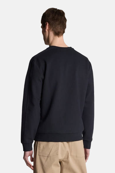 Sweat-shirt bleu marine de LYLE & SCOTT, avec des manches longues et porté avec un pantalon beige.